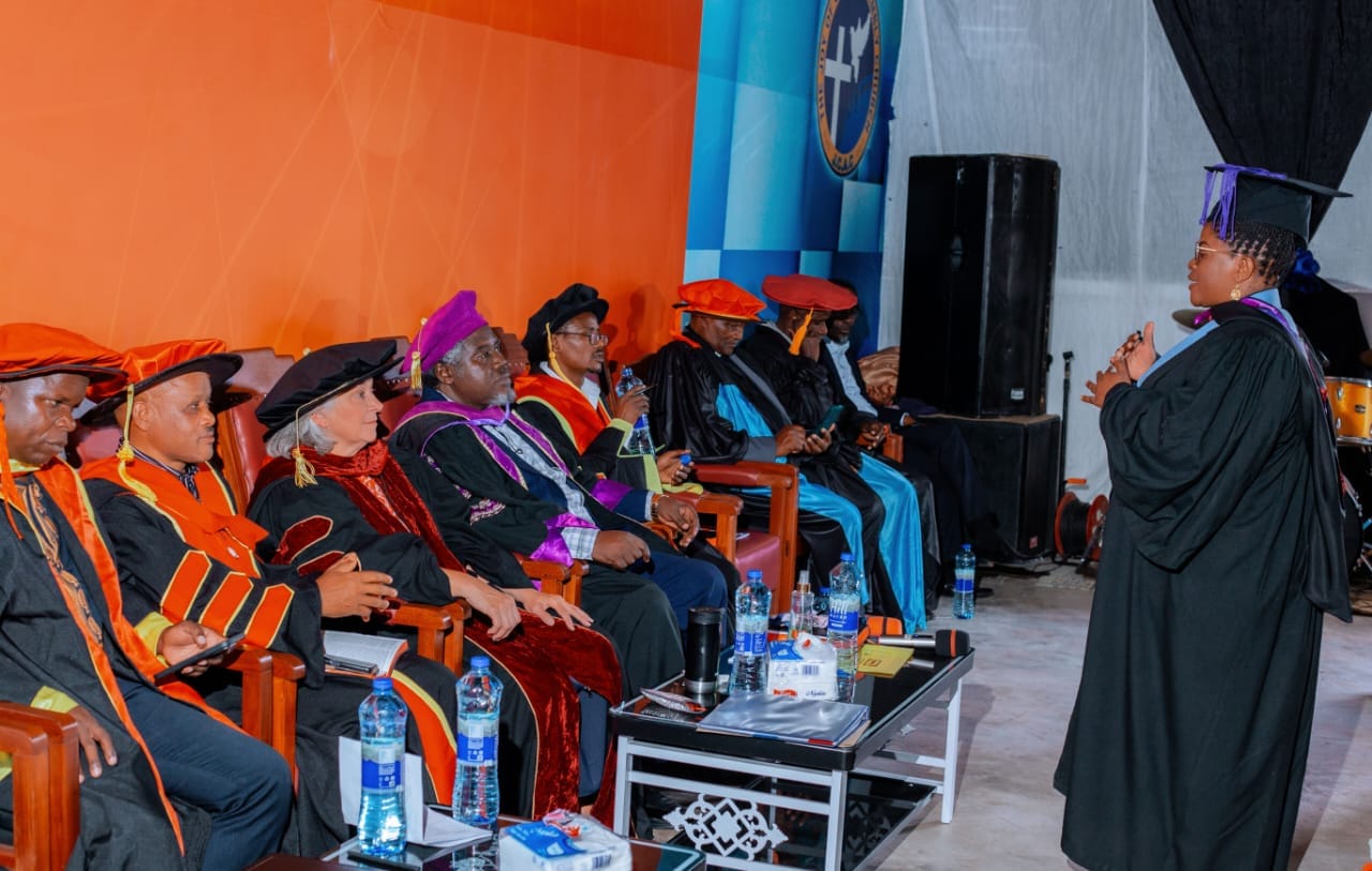A speaker in academic regalia addressing seated faculty